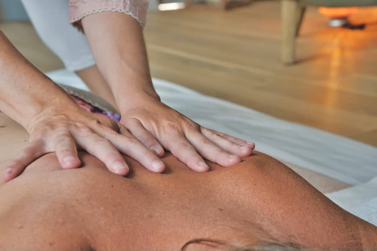 A therapist's hands resting gently on a client's back during a relaxing therapeutic massage session, highlighting first-time expectations.
