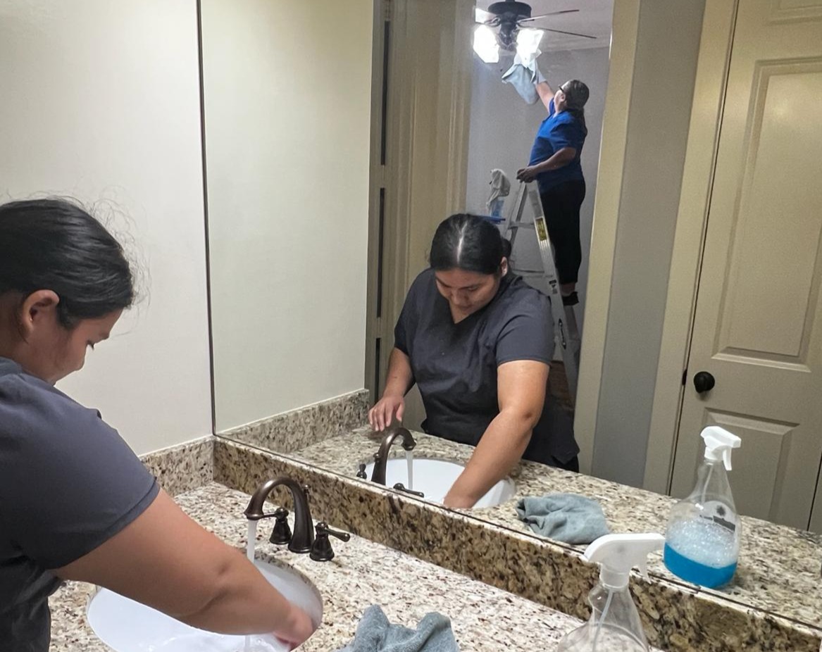 An orange truck driving down a street next to a tall building