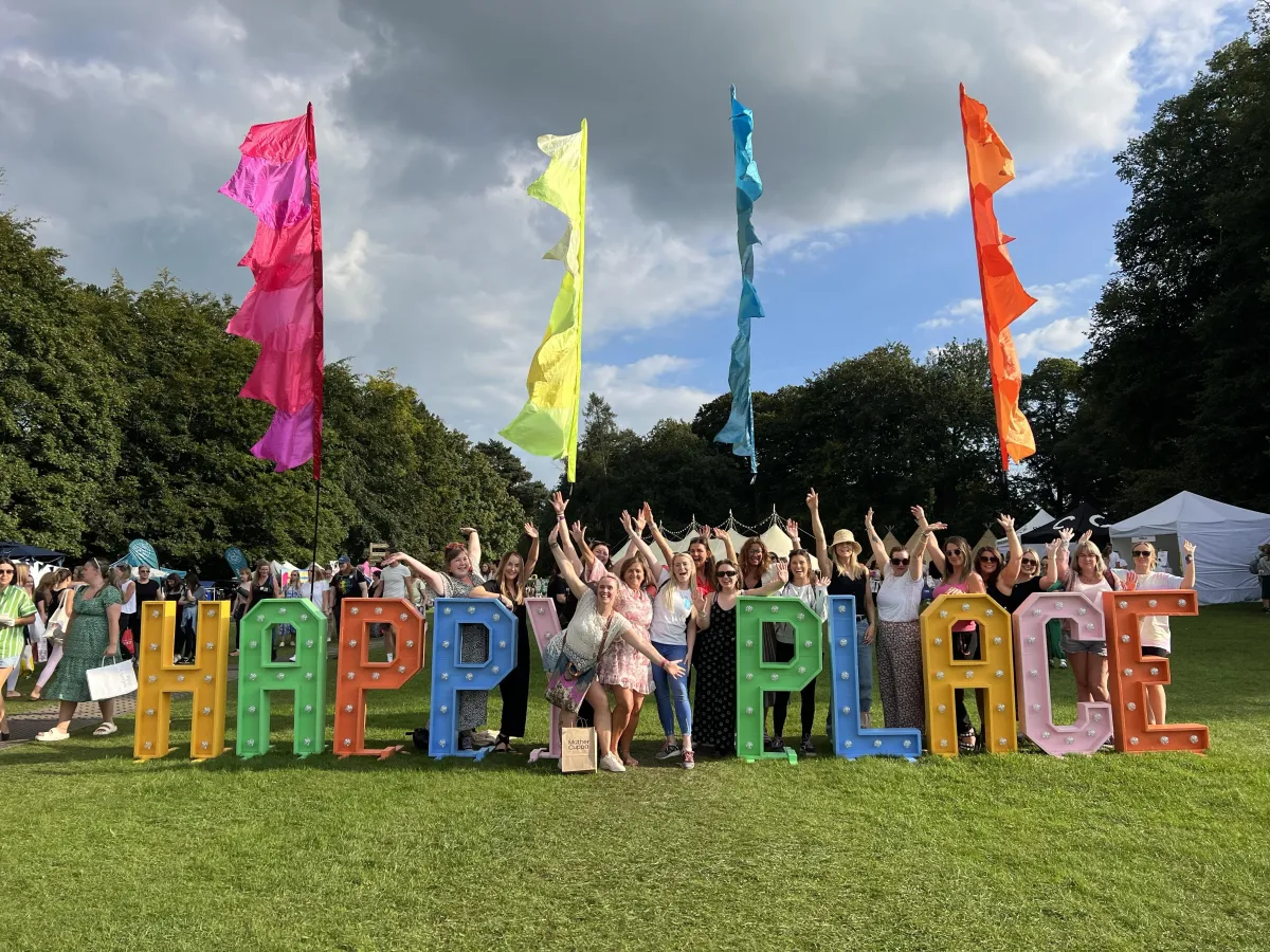 People looking happy standing next to a giant sign that says HAPPY PLACE