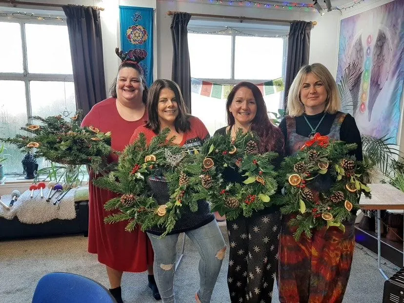 4 women holding up home-made Christmas wreaths