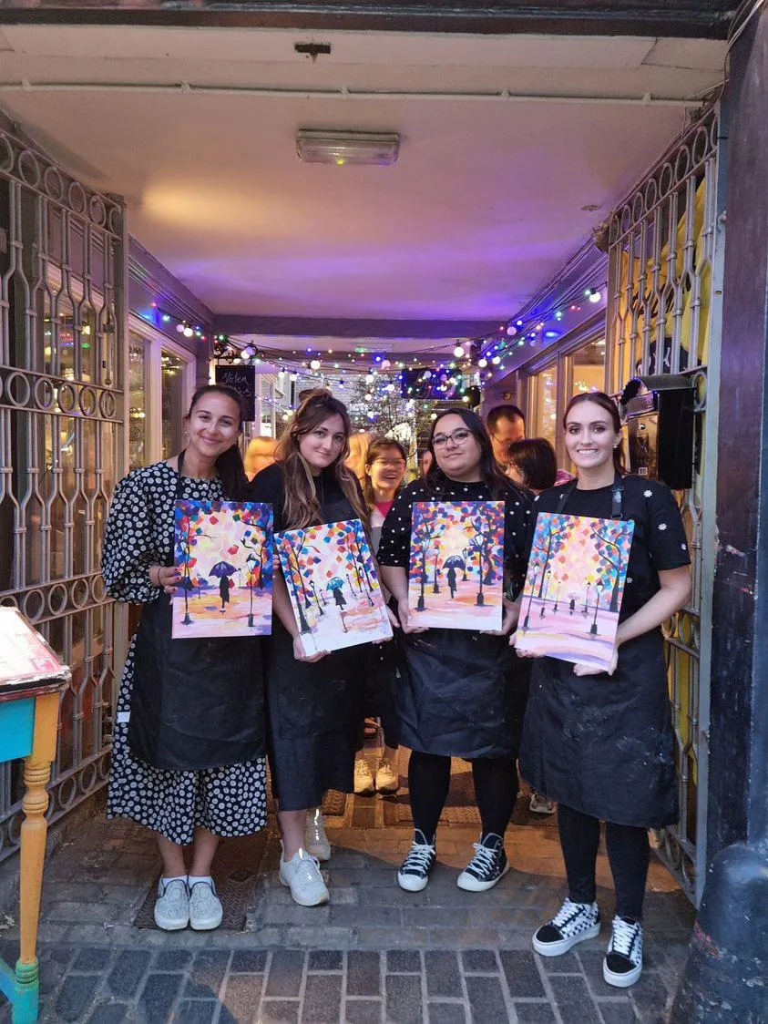 4 women holding paintings they have made