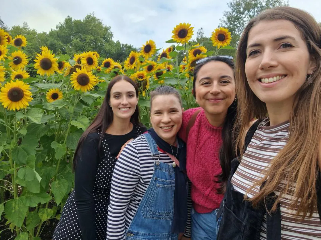 4 young women standing in a field of sunflowers