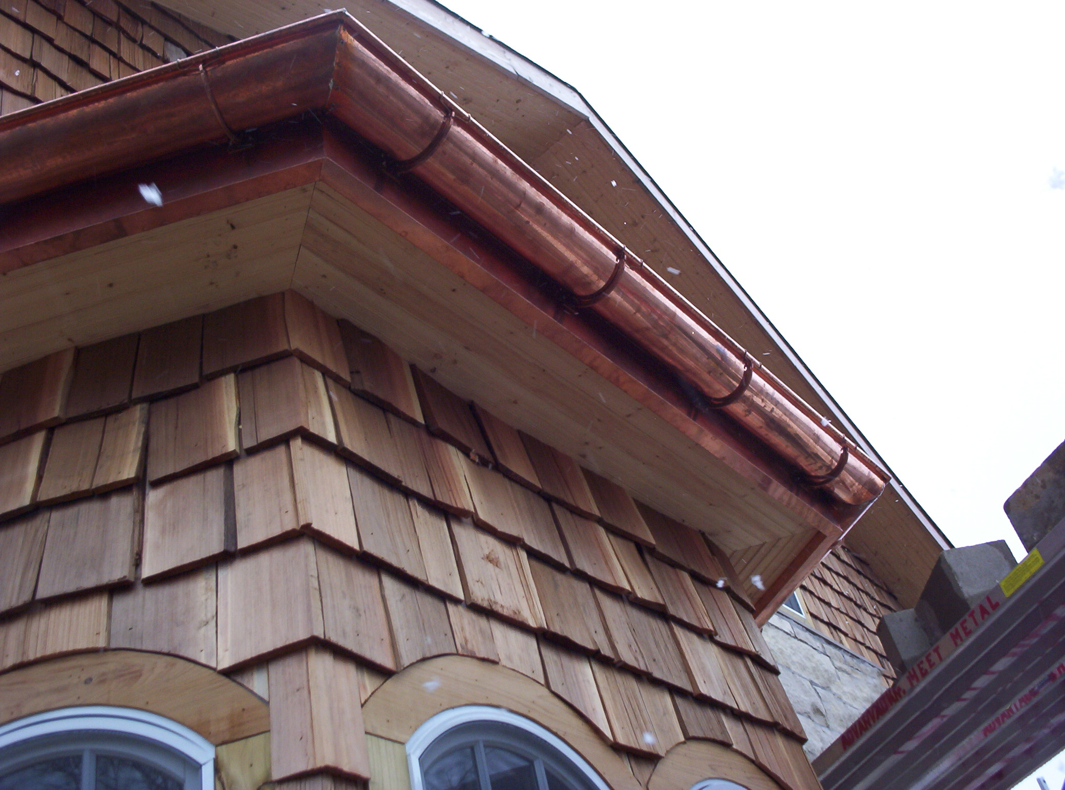 Copper rain gutter and downspout on home exterior.
