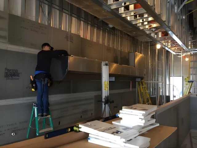 HVAC technician installing ductwork in a commercial building.