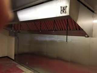 Commercial kitchen ventilation ductwork and exhaust system above cooking area.