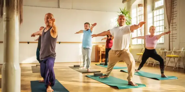 Group of adults practicing yoga poses to improve balance, coordination, mobility, and body awareness