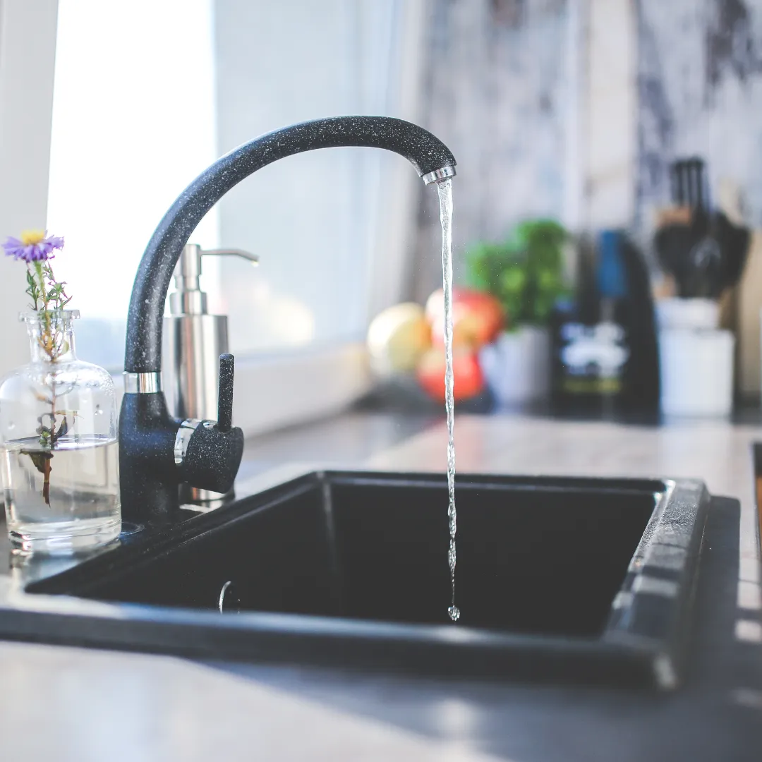 A plumber installing new bathroom fixtures, including a sink, faucet, and toilet, as part of a home renovation project.