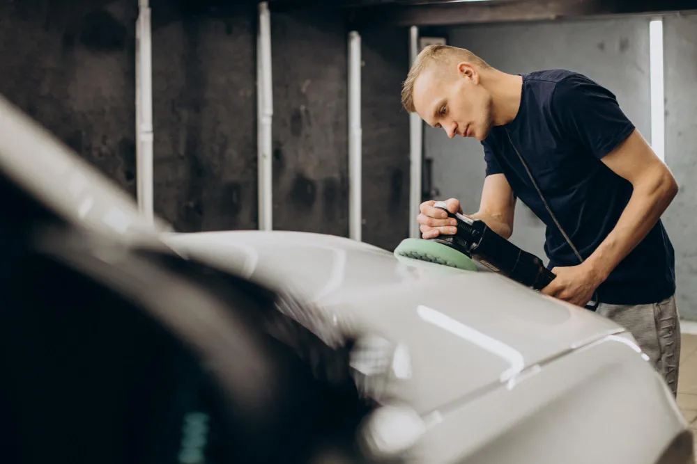 Mechanic writing on a clipboard while standing next to a car
