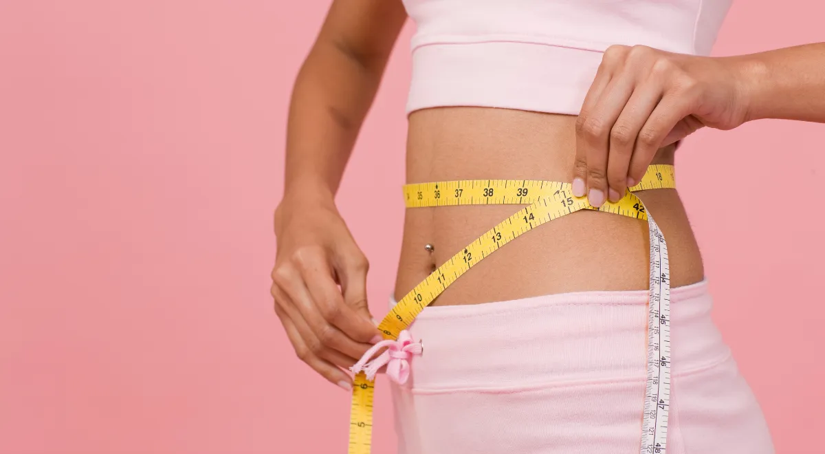 Woman wrapping measuring tape around her waist