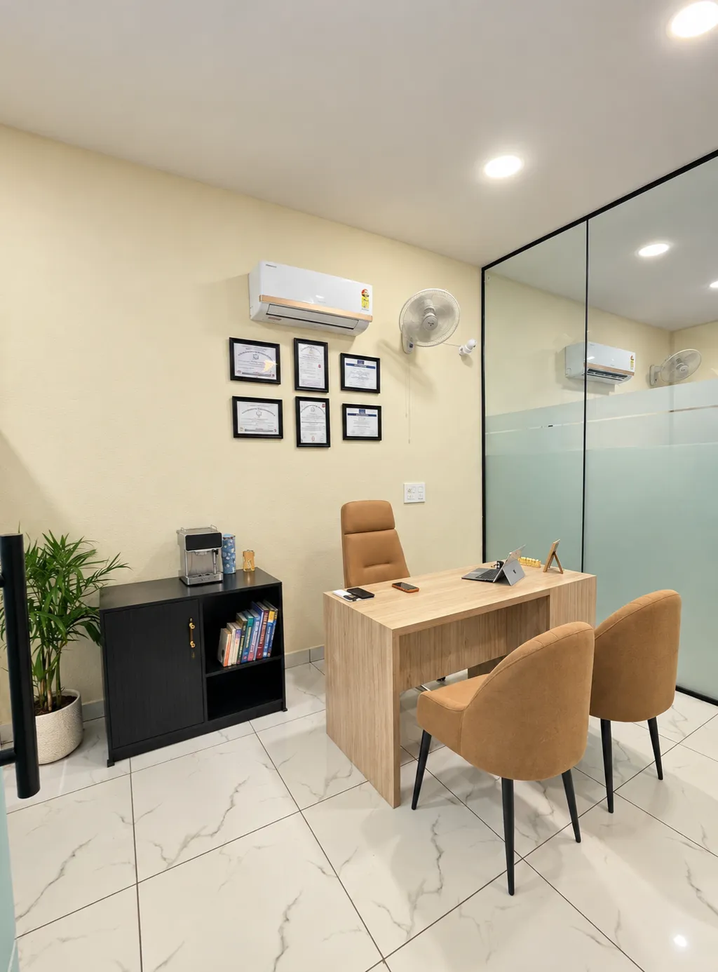 Waiting area with beige armchairs, small table, and plant.