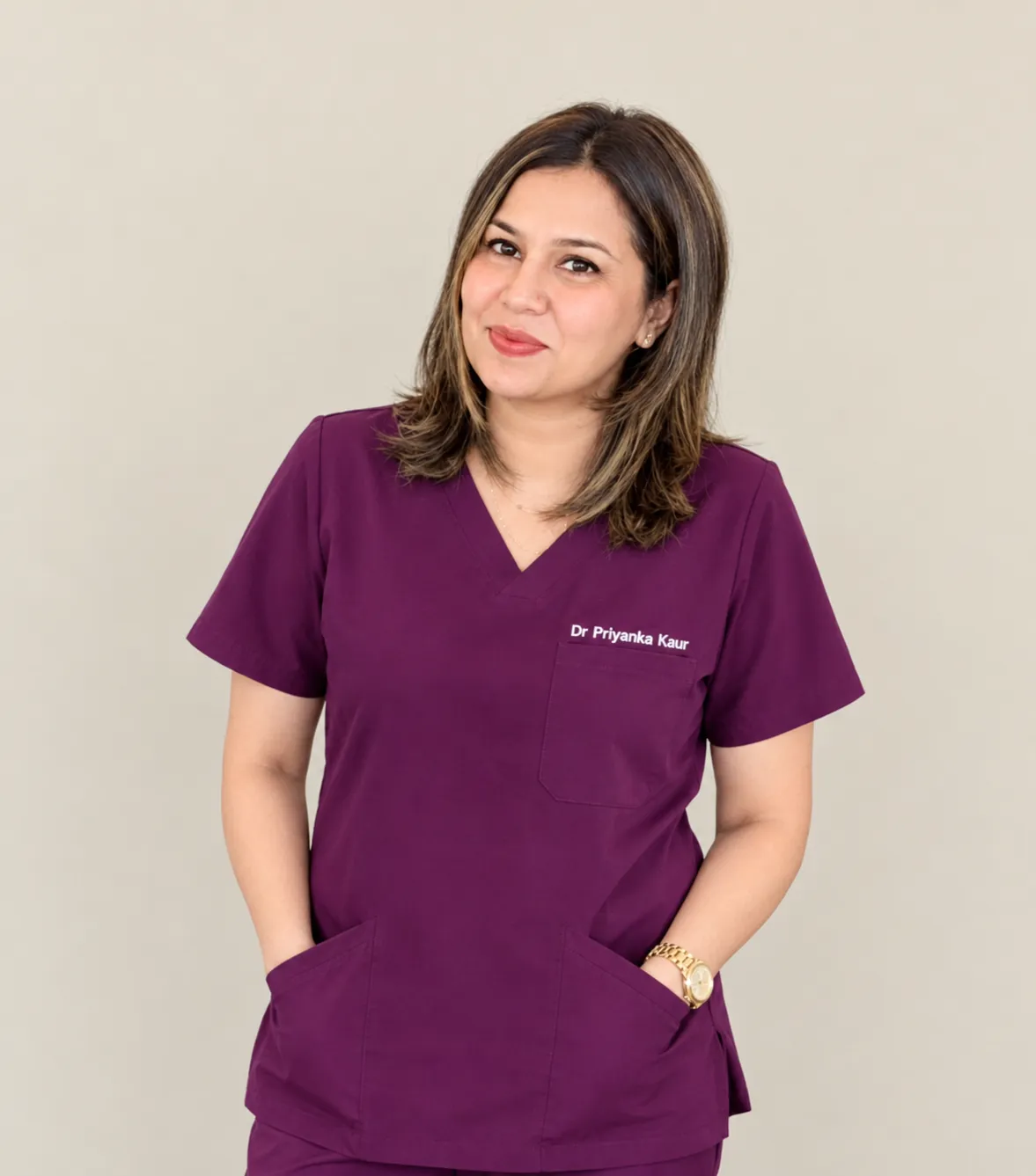 Smiling female dentist in a white coat with arms crossed, in front of a blurred clinic background.