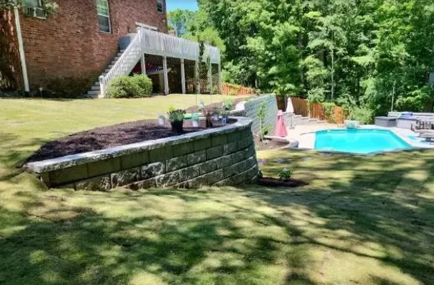 Stone retaining wall next to a clean backyard pool area for erosion control and style