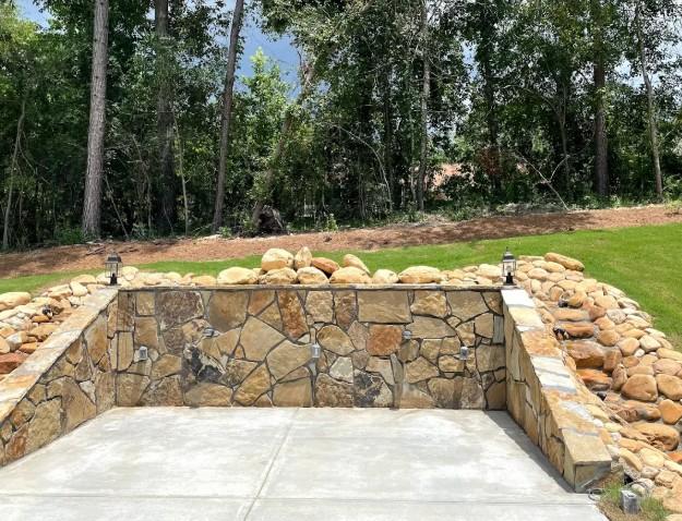 Curved rock retaining wall enclosing a landscaped seating space in a private yard