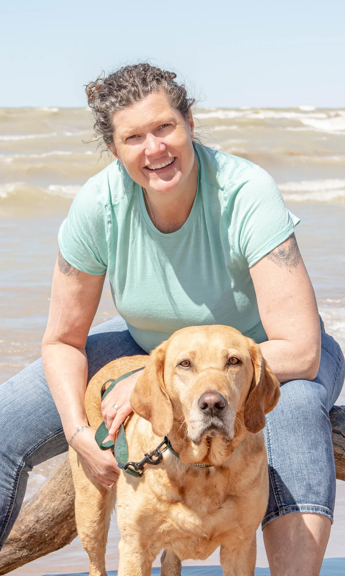 Woman sitting in a field with two dogs