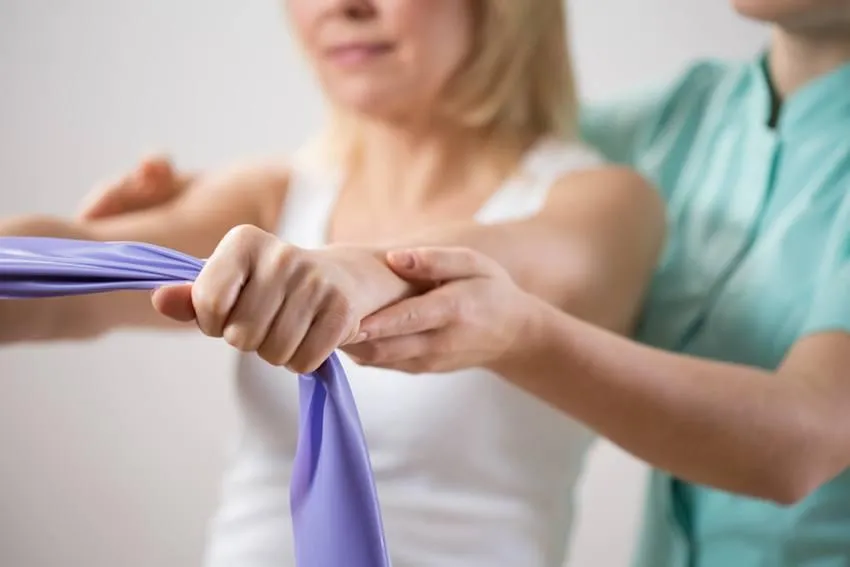 Patient performing a guided resistance band exercise with a therapist for arm and shoulder rehabilitation.