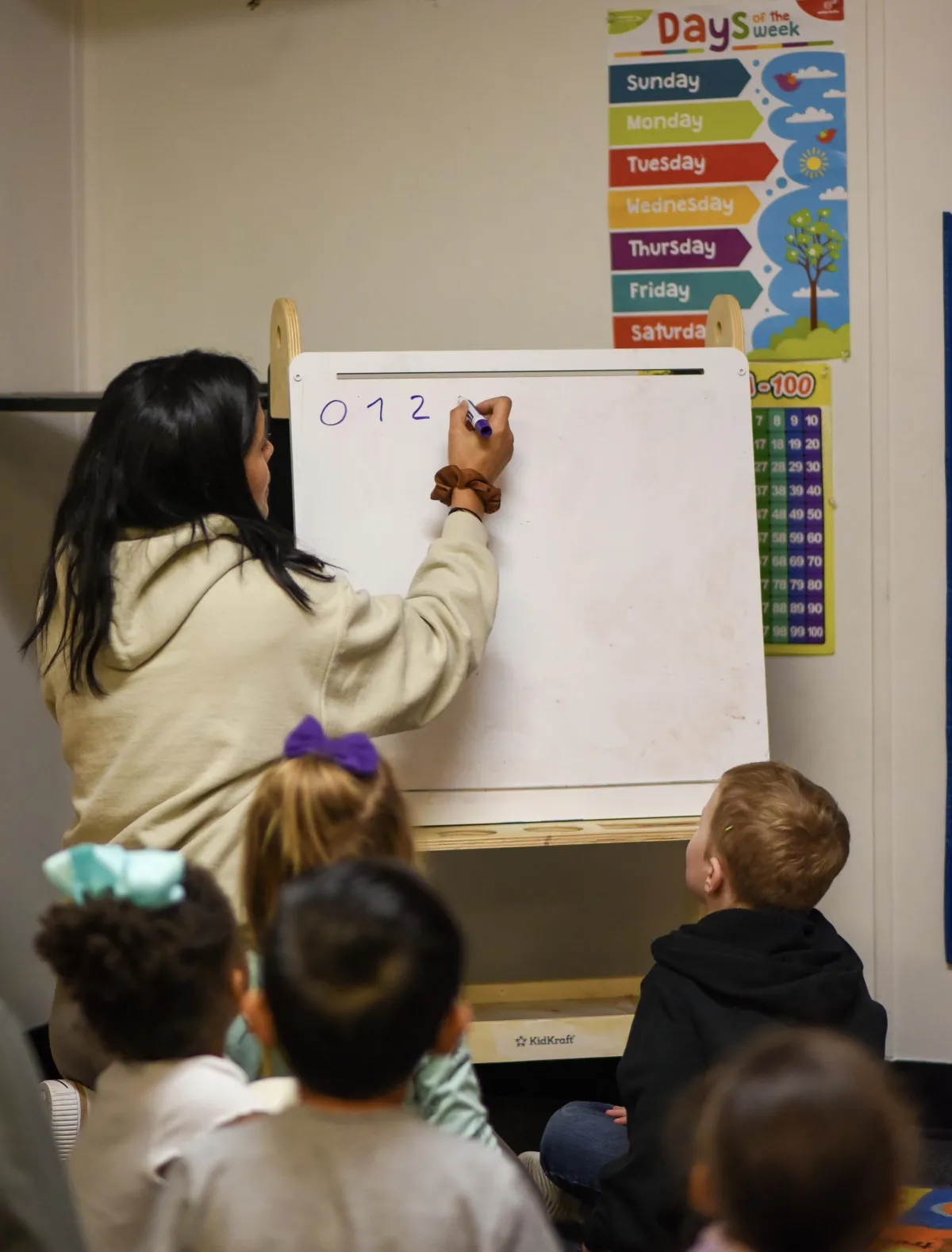 Girl stretches to the side while watching teacher on large screen TV