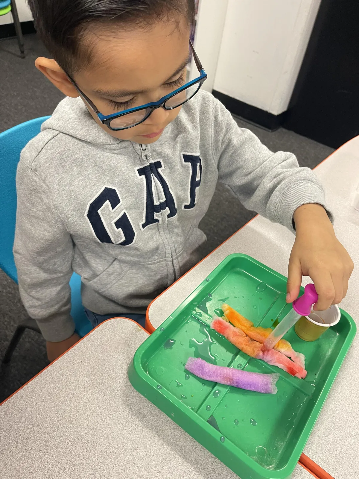 Boy picks paper out of different colored liquids