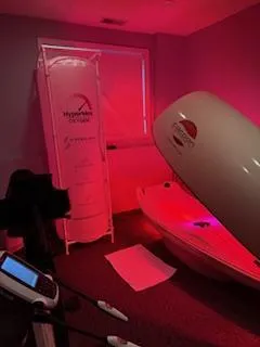 a woman laying in a bathtub next to a bottle of essential oils