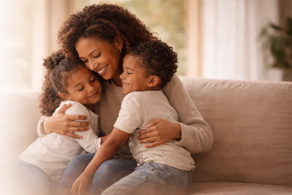 Smiling mother holding her son and daughter representing support and encouragement for moms