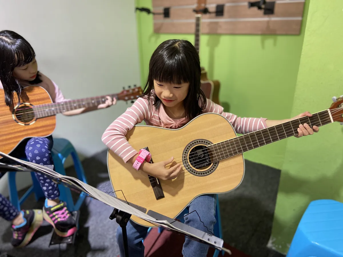 Group of children learning to play guitar