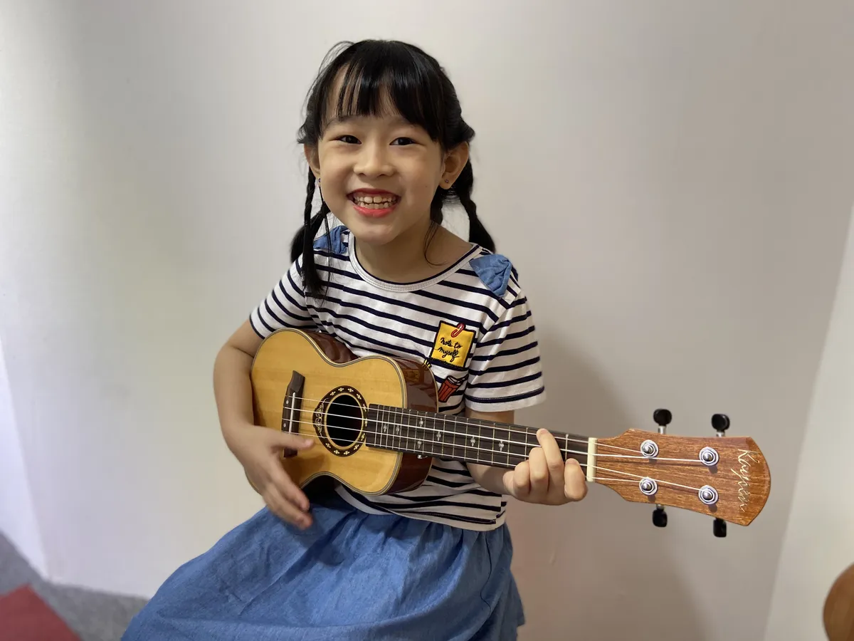 Children leaning to play Ukulele