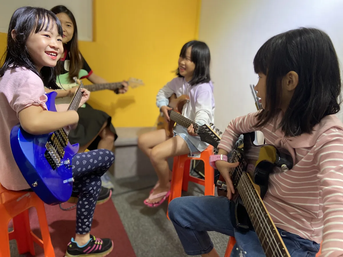 Diverse group of music students practicing acoustic guitars together in an encouraging workshop circle