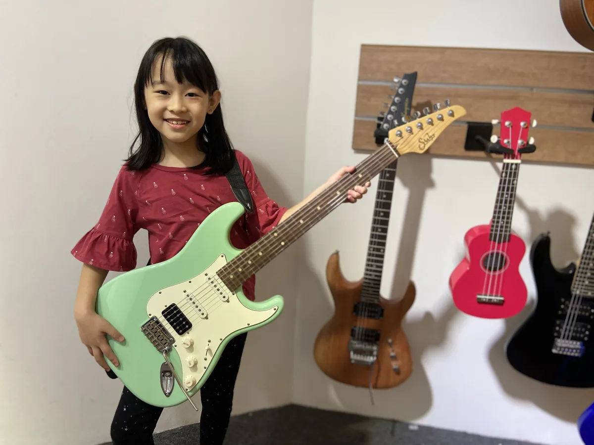 Enthusiastic music student holding a guitar with confidence