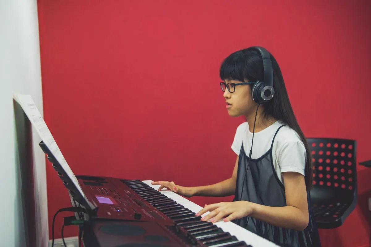 Enthusiastic music school student practicing on a keyboard in a modern group class setting