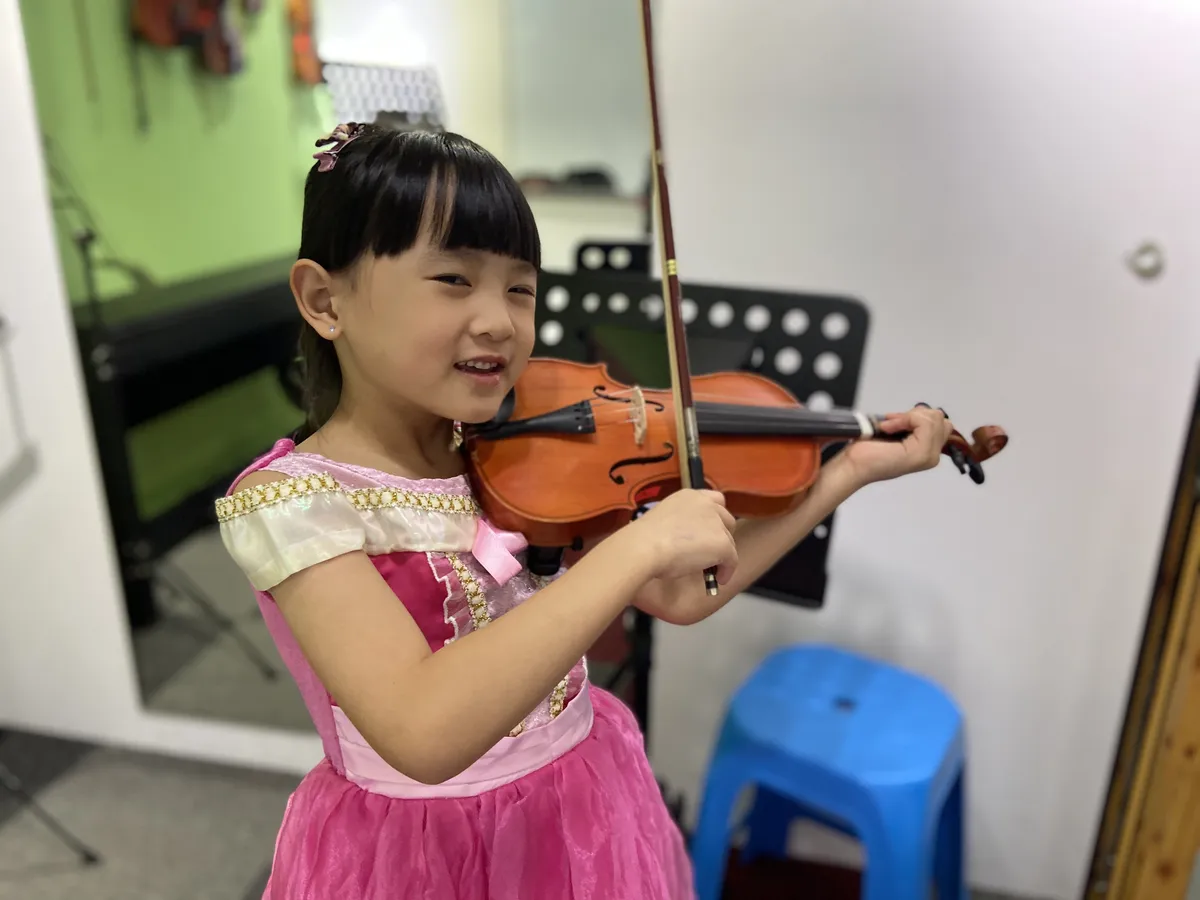 Student learning violin in a modern music school lesson setting