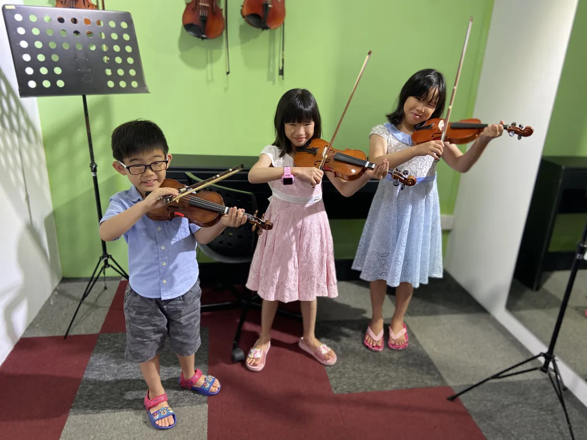 Small group violin lesson in a music school with students practicing together