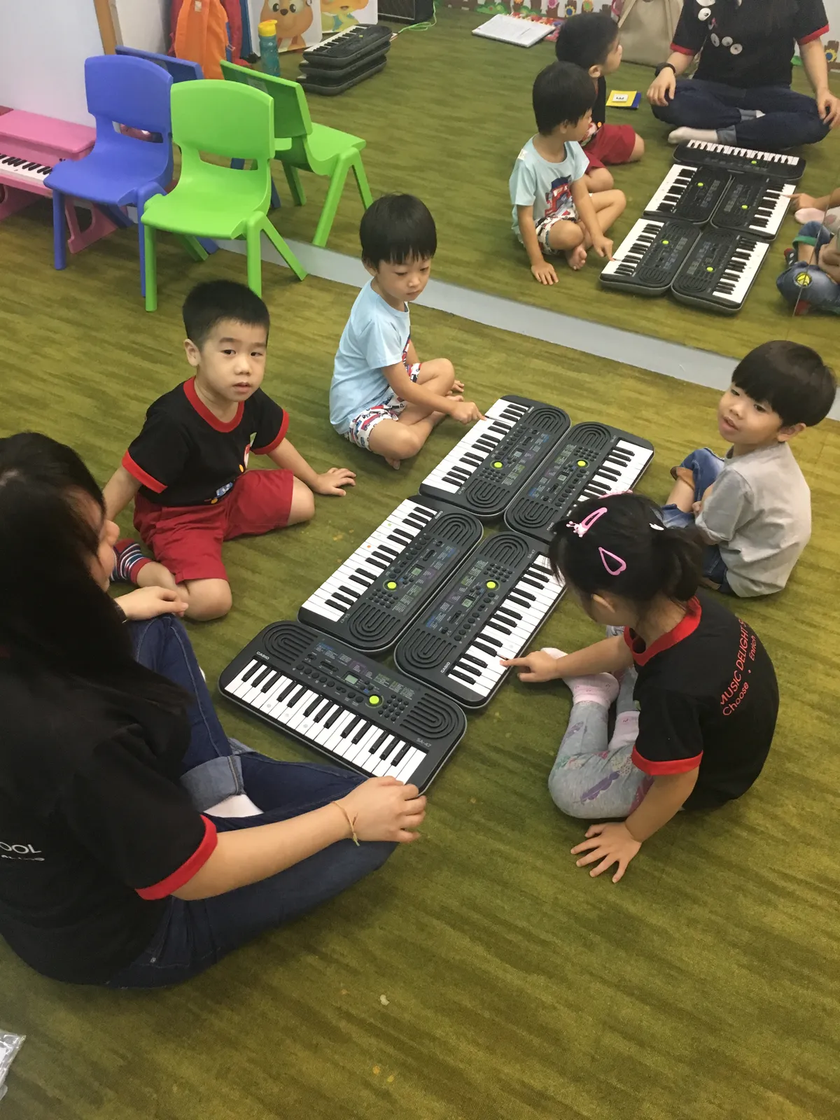 Young child exploring an electronic keyboard with gentle guidance in a music school studio