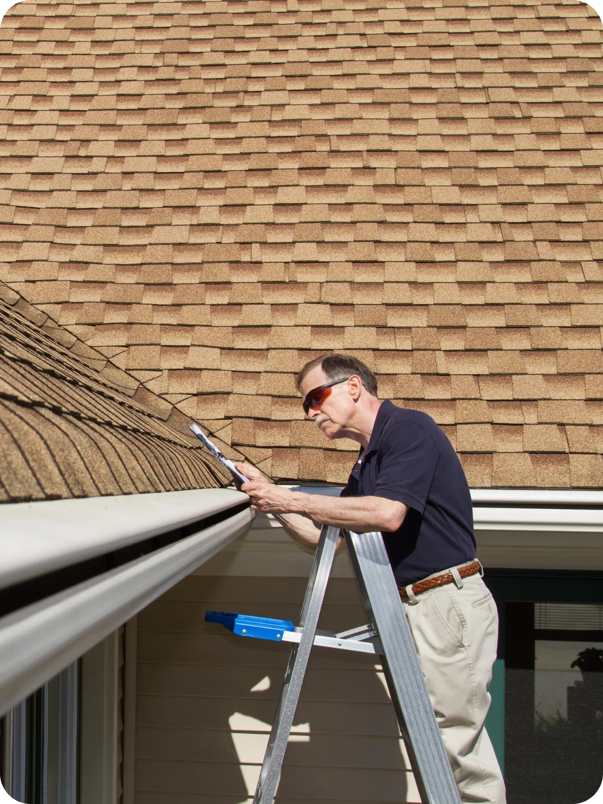 Home inspector on a ladder examining roof shingles during a detailed home inspection in Fort Collins, CO.