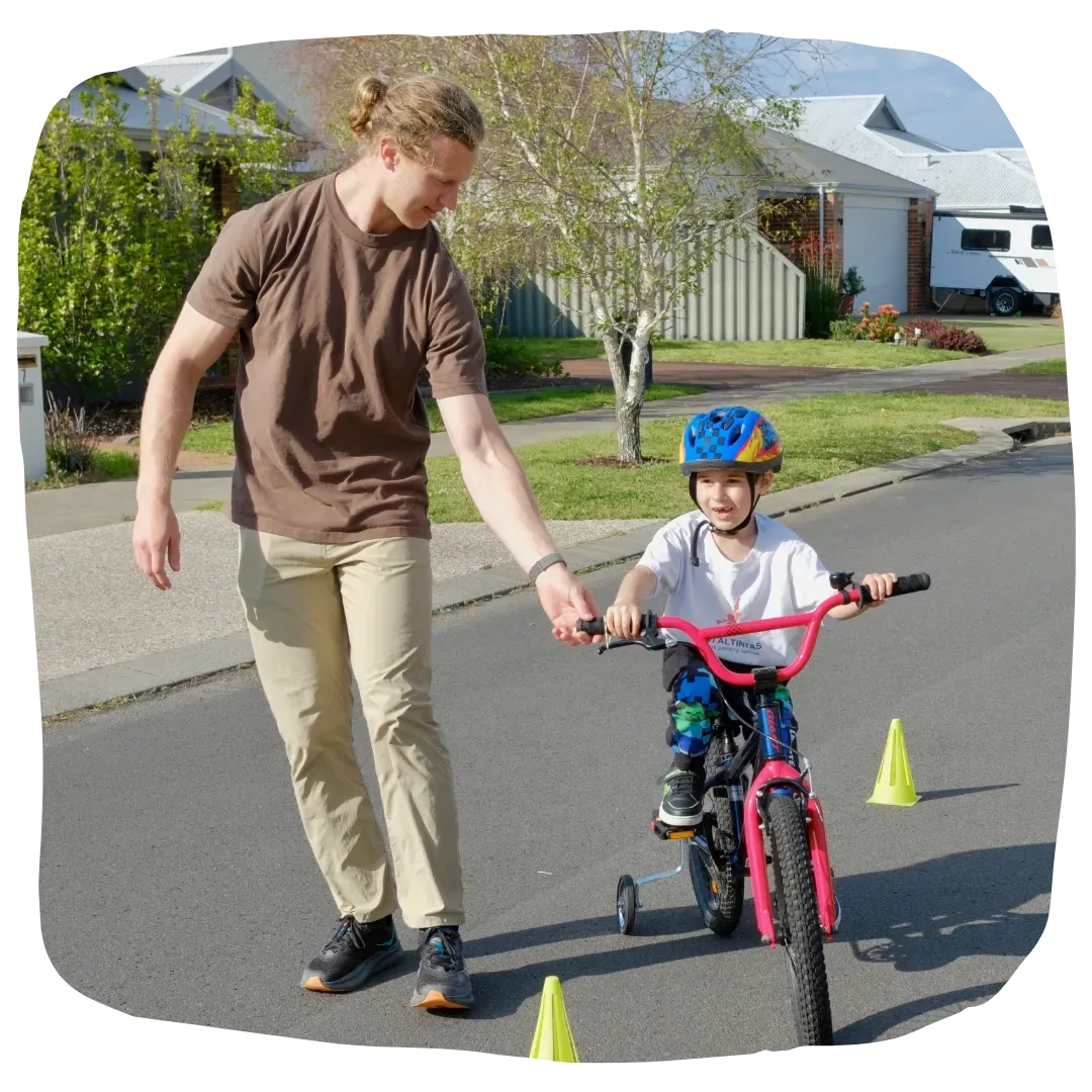 Paediatric Physiotherapist Assisting Kid Ride a Bike