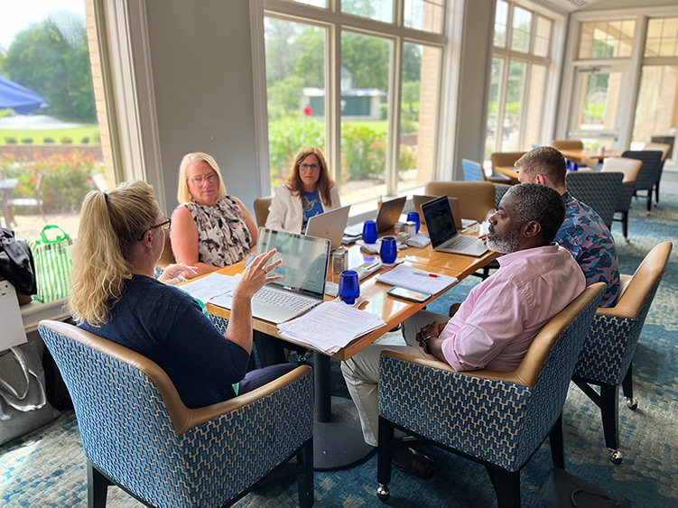 Diverse group of business professionals collaborating around a table with laptops during an executive strategy meeting