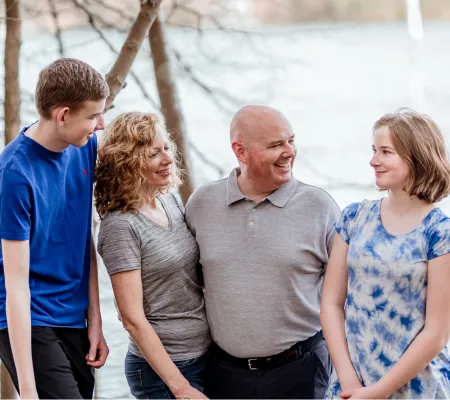 two parents and a middle school son look at a tween girl who is smiling