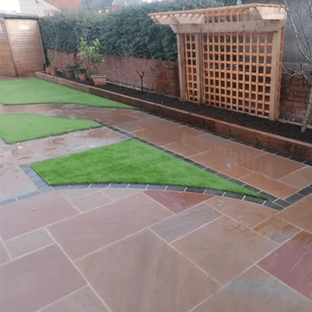 Back garden with patio slabs, astroturf and side planters made from wooden sleepers