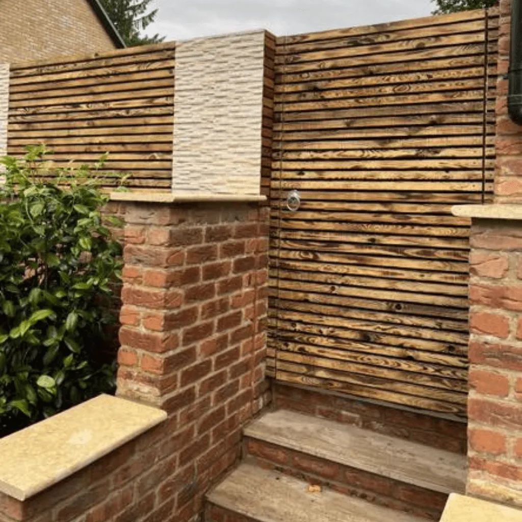 Wooden fence and gate in between brick pillars