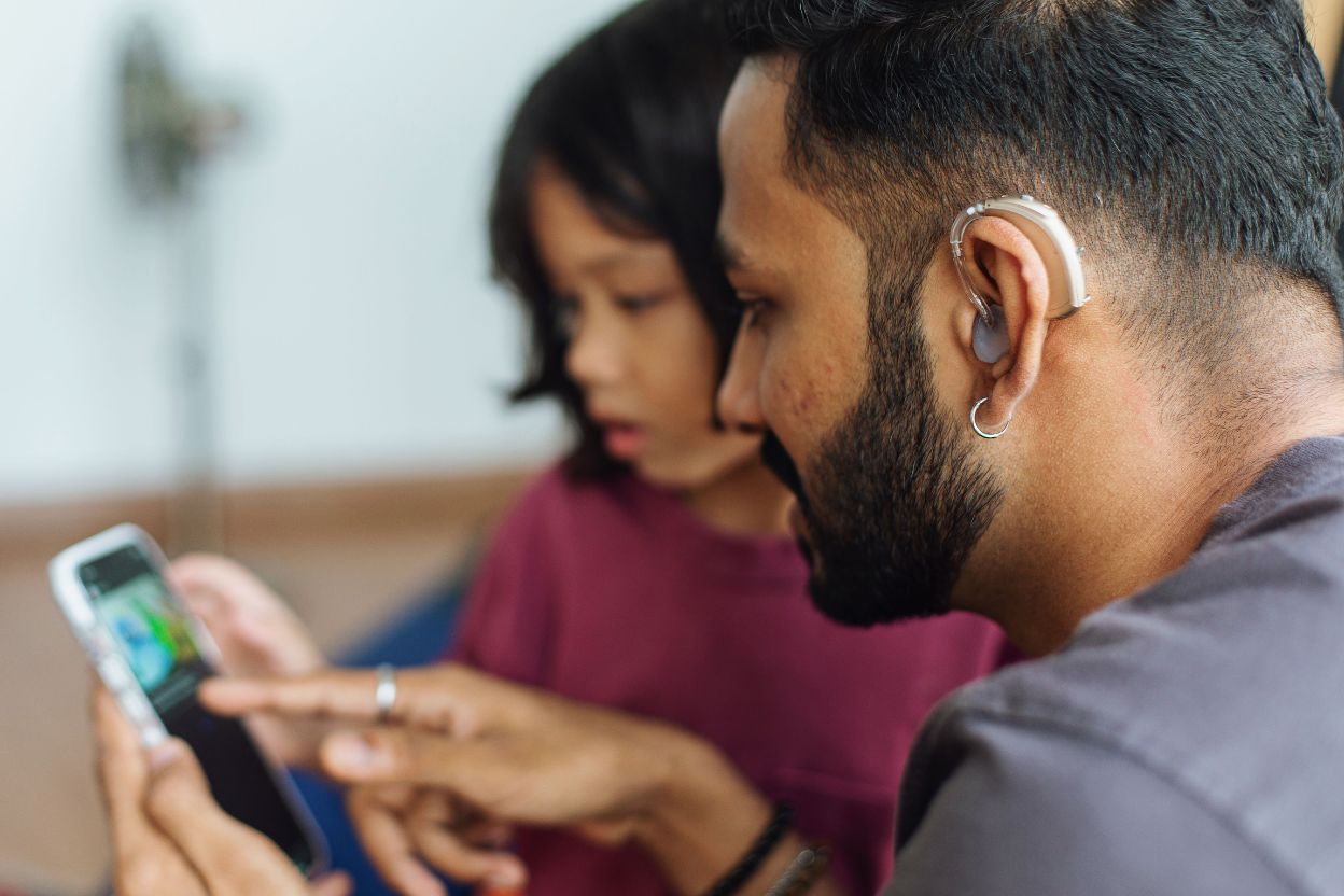 man with hearing aids watching a video with his daughter