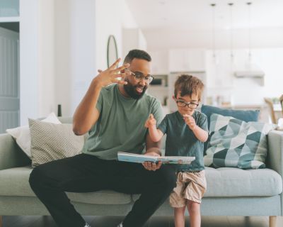 father and son on the couch talking and reading a book