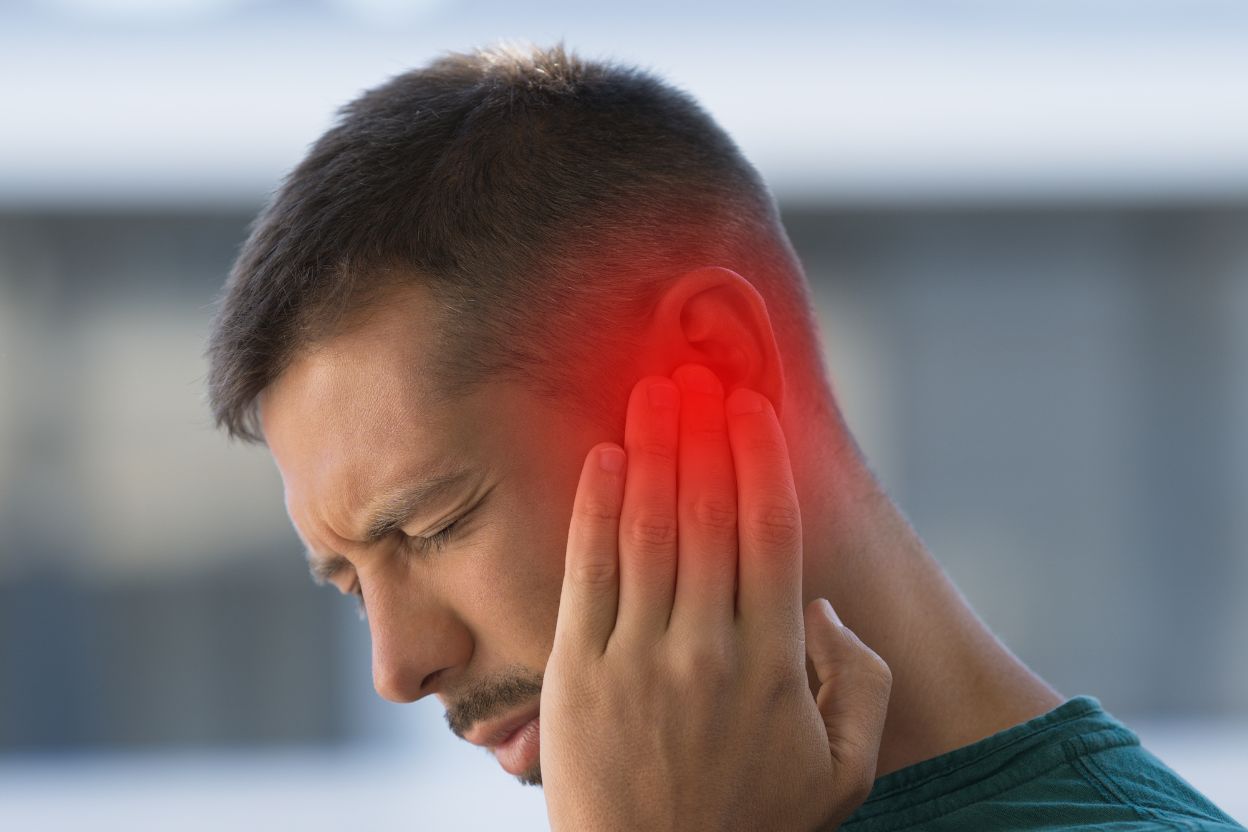 man holding his ear in pain and the ear is glowing red