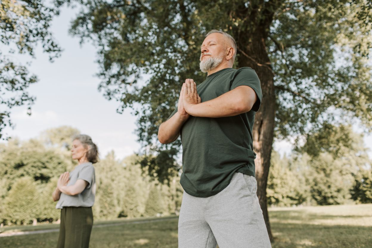 older couple doing yoga in the park