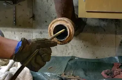 Drain cleaning service using auger to clear clogged pipe