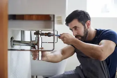 Technician repairing water heater connections and supply lines