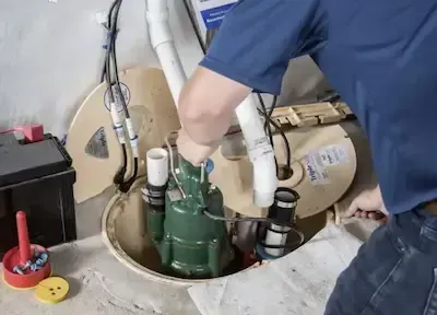 Technician servicing sump pump system inside basement pit