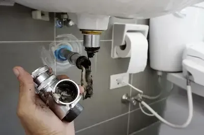 Clogged bathroom sink drain removed and cleaned during plumbing repair