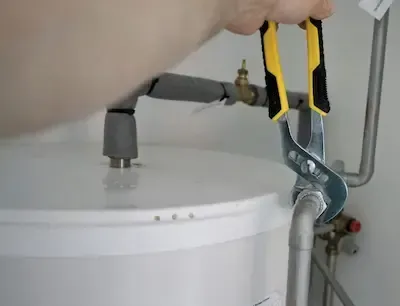 Tightening water heater connection during plumbing repair service