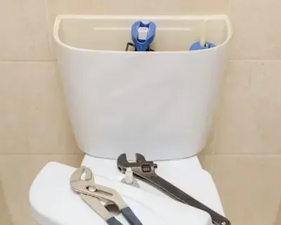 Toilet repair tools placed on tank during bathroom plumbing fix