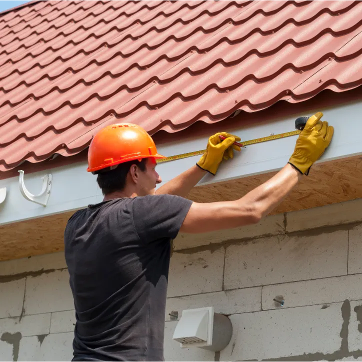 Worker measuring a house for gutters