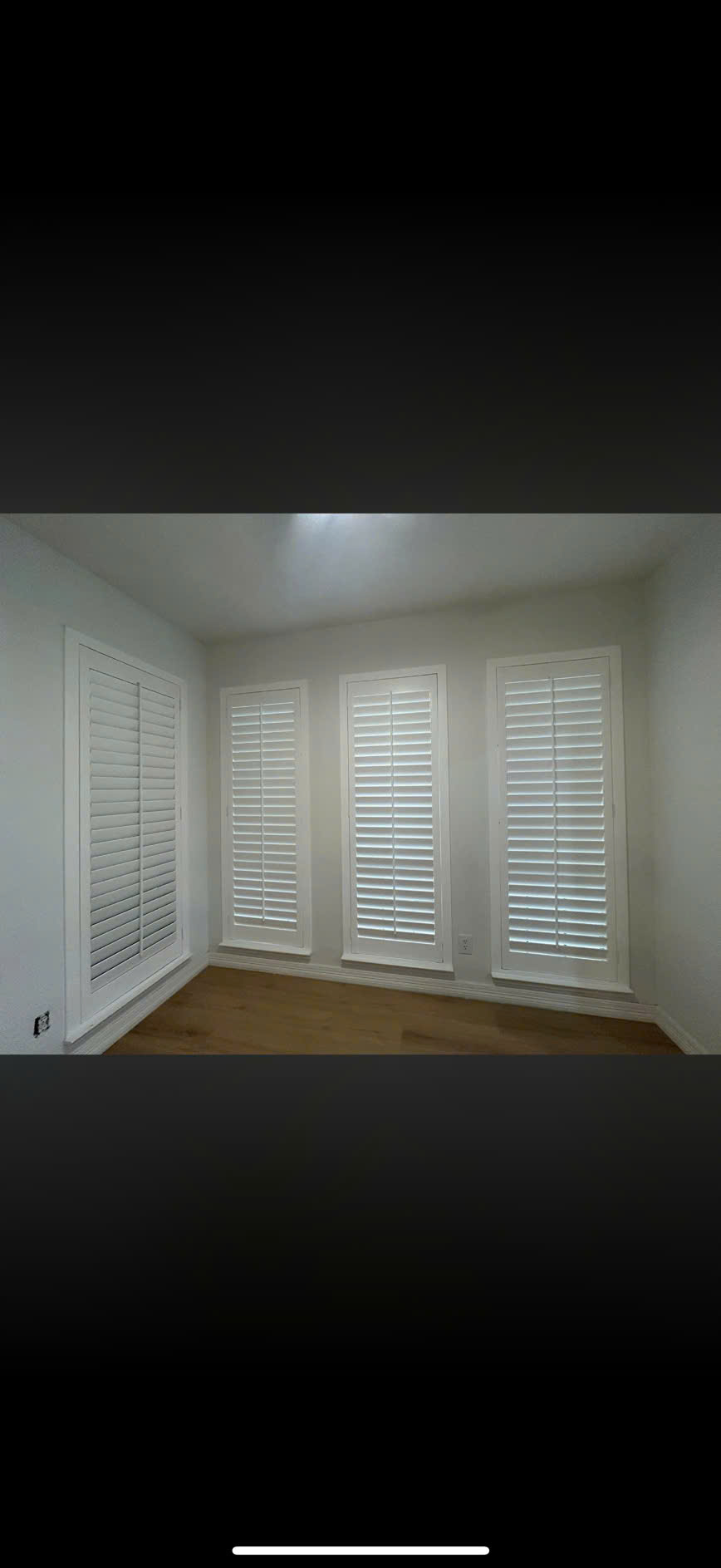 Custom white plantation shutters installed in a bright living room