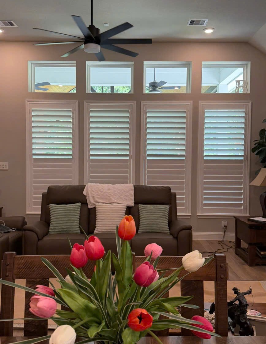 White plantation shutters installed across four living room windows
